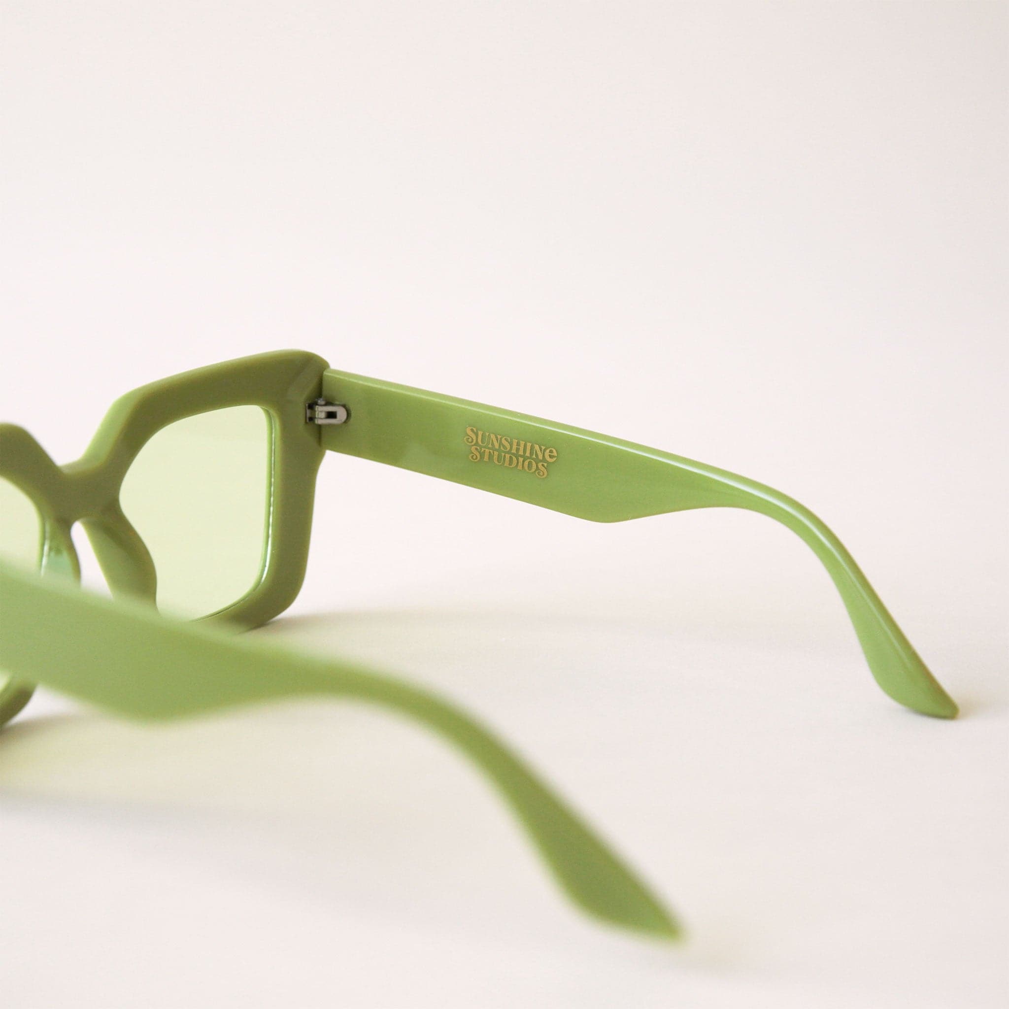 70&#39;s inspired sunglasses with a lime green, rectangle frame that has a slight cat eye point at the tops along with light green lenses.