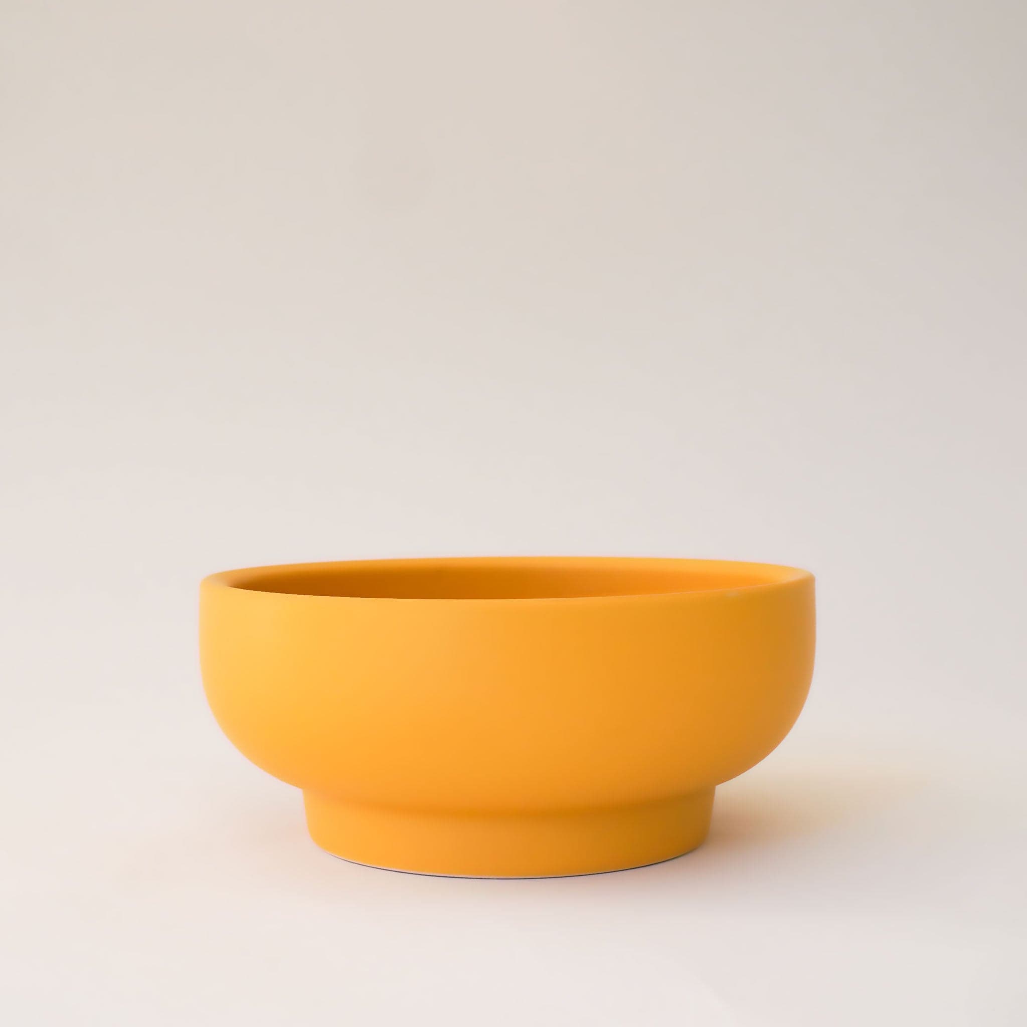 Bright orange bowl planter that tapers towards the base. 