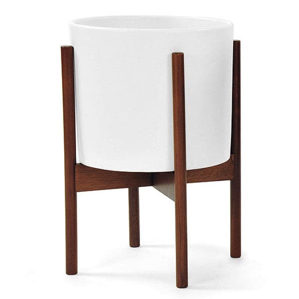 One white stoneware ceramic pot sits on a walnut wooden stand. The pot is nestled within the stand&#39;s four extended legs.