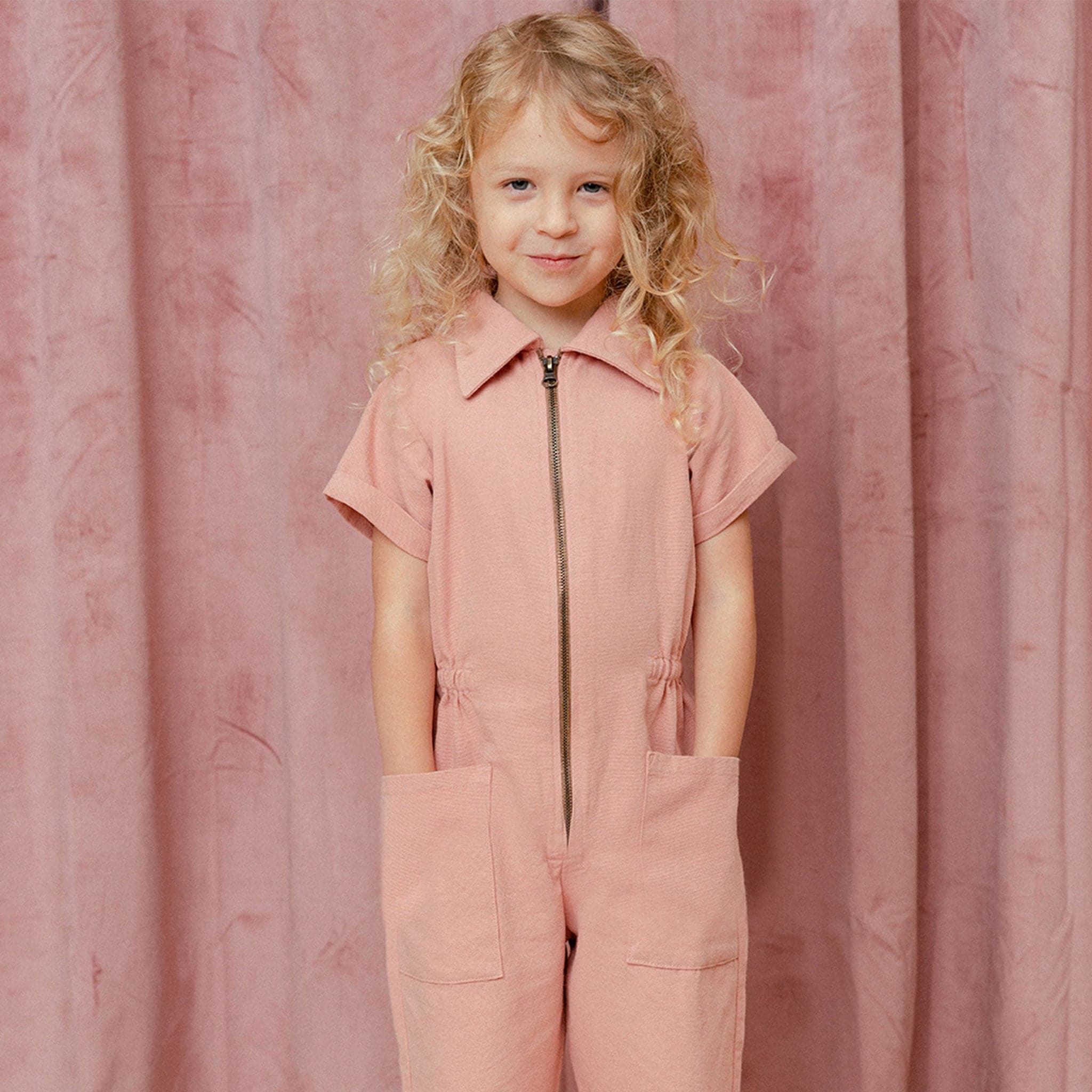 A short sleeved utility jumpsuit in the sweetest dusty rose shade. There is a front zipper and a two pockets.