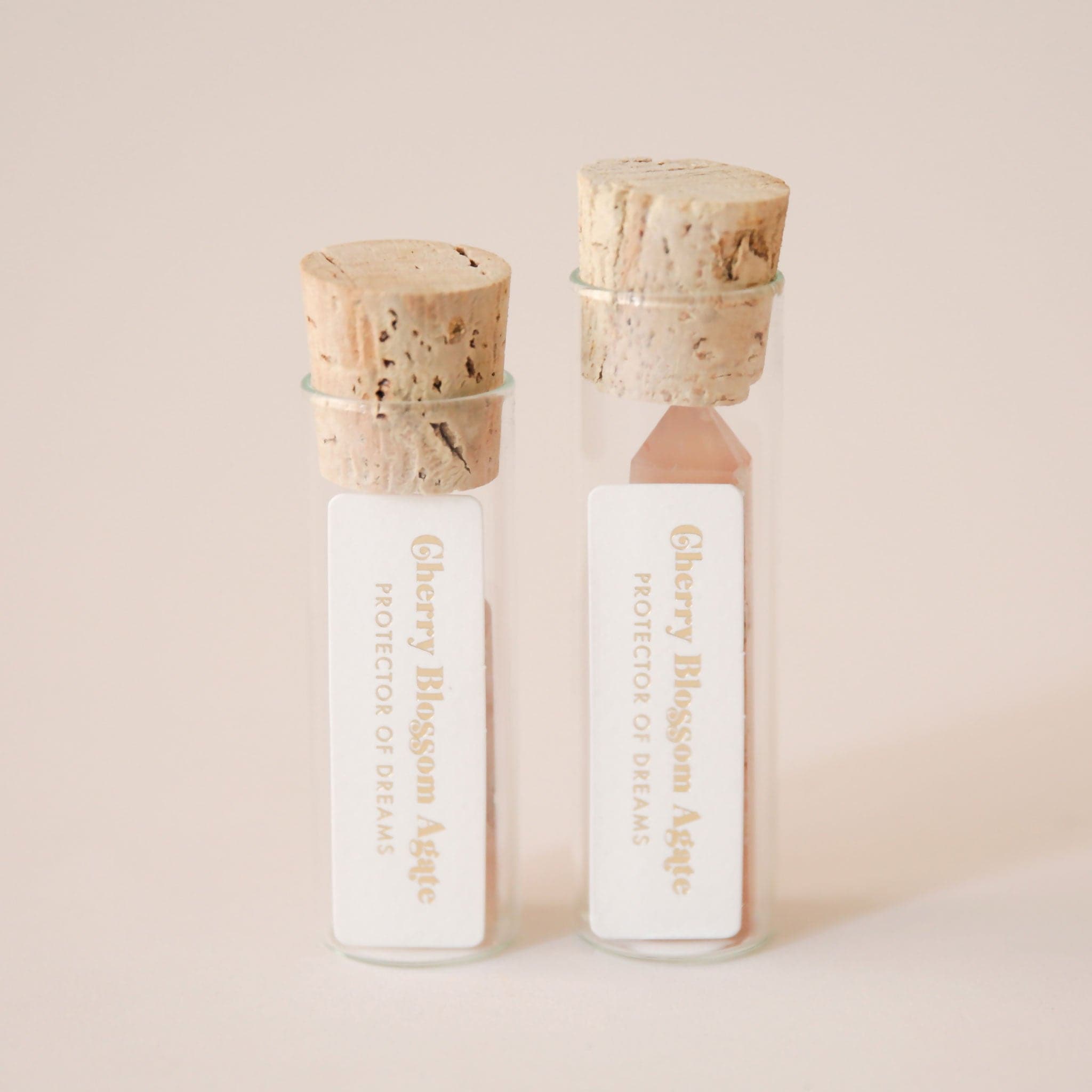 A photo of our packaging that each crystal is sold in. A glass tube holds the crystal while the top is secured by a round cork. The packaging also includes a paper with the name of the crystal and its general meaning and purpose.