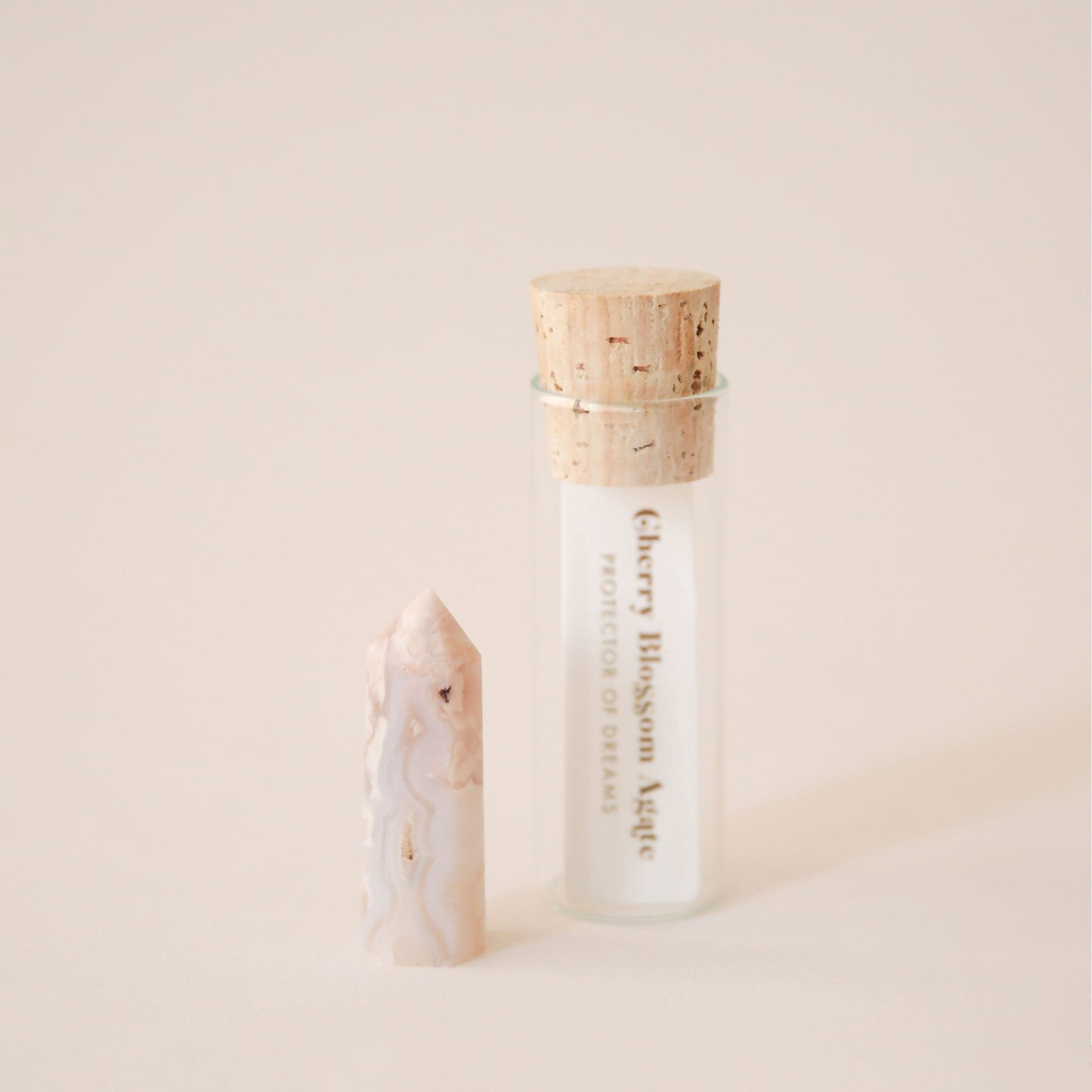 A photo of our packaging that each crystal is sold in. A glass tube holds the crystal while the top is secured by a round cork. The packaging also includes a paper with the name of the crystal and its general meaning and purpose.