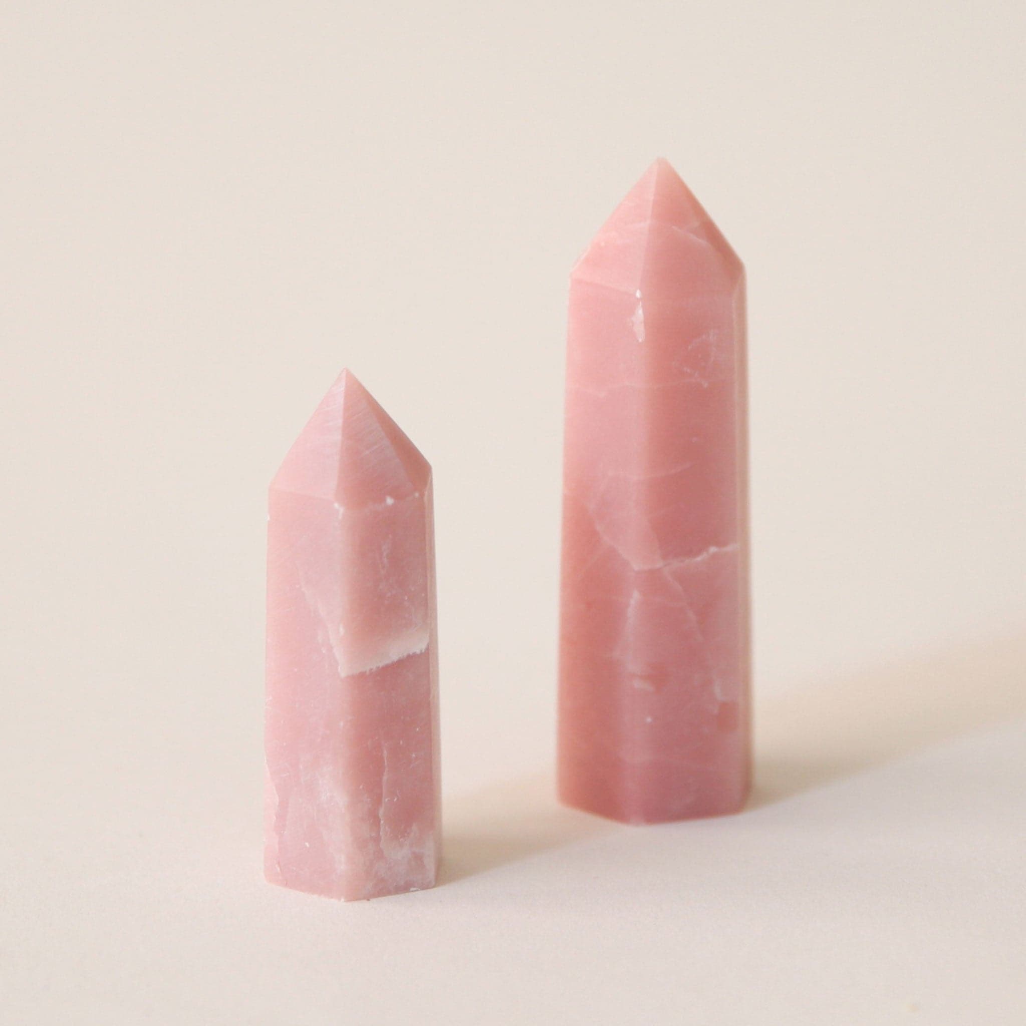 Two different sized pink opal point crystals with a white marbling.'