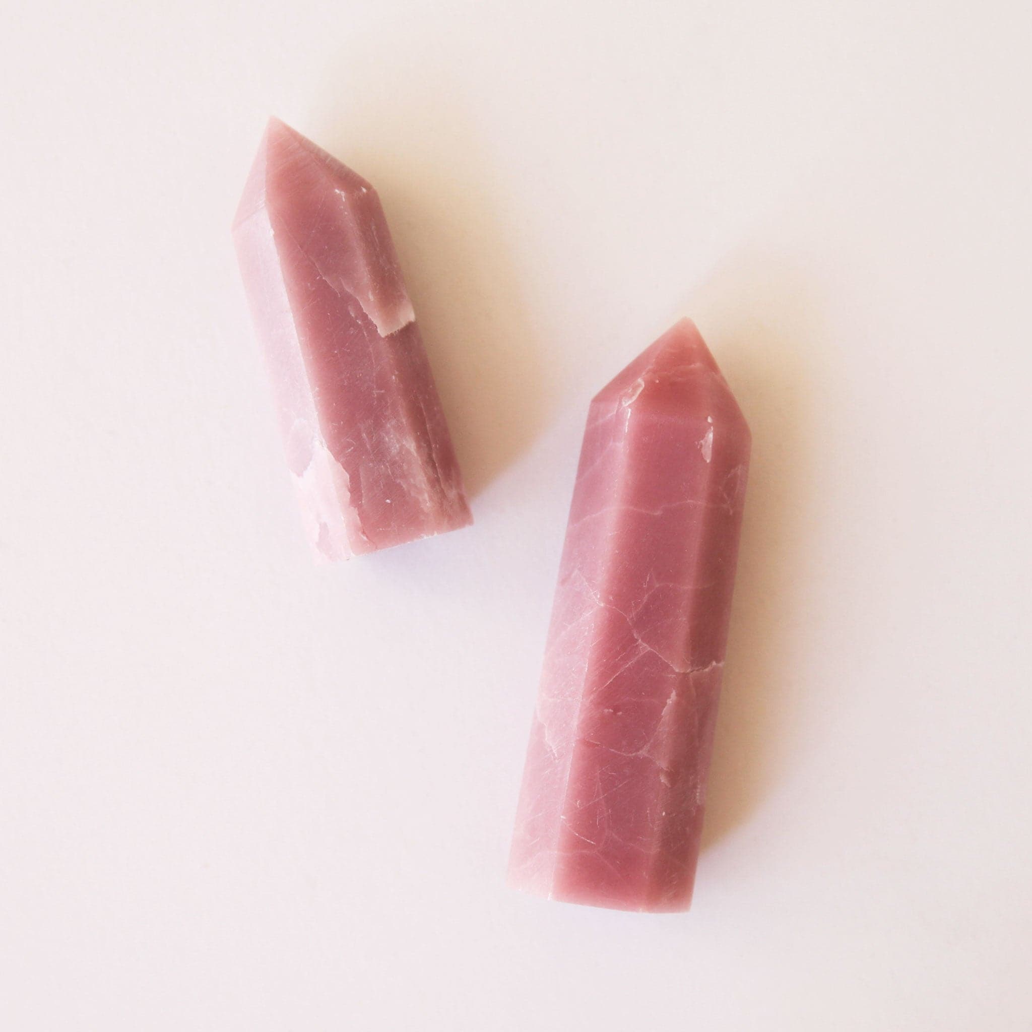 Two different sized pink opal point crystals with a white marbling.