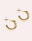 Chunky gold huggie hoop earrings with a straight post backing.