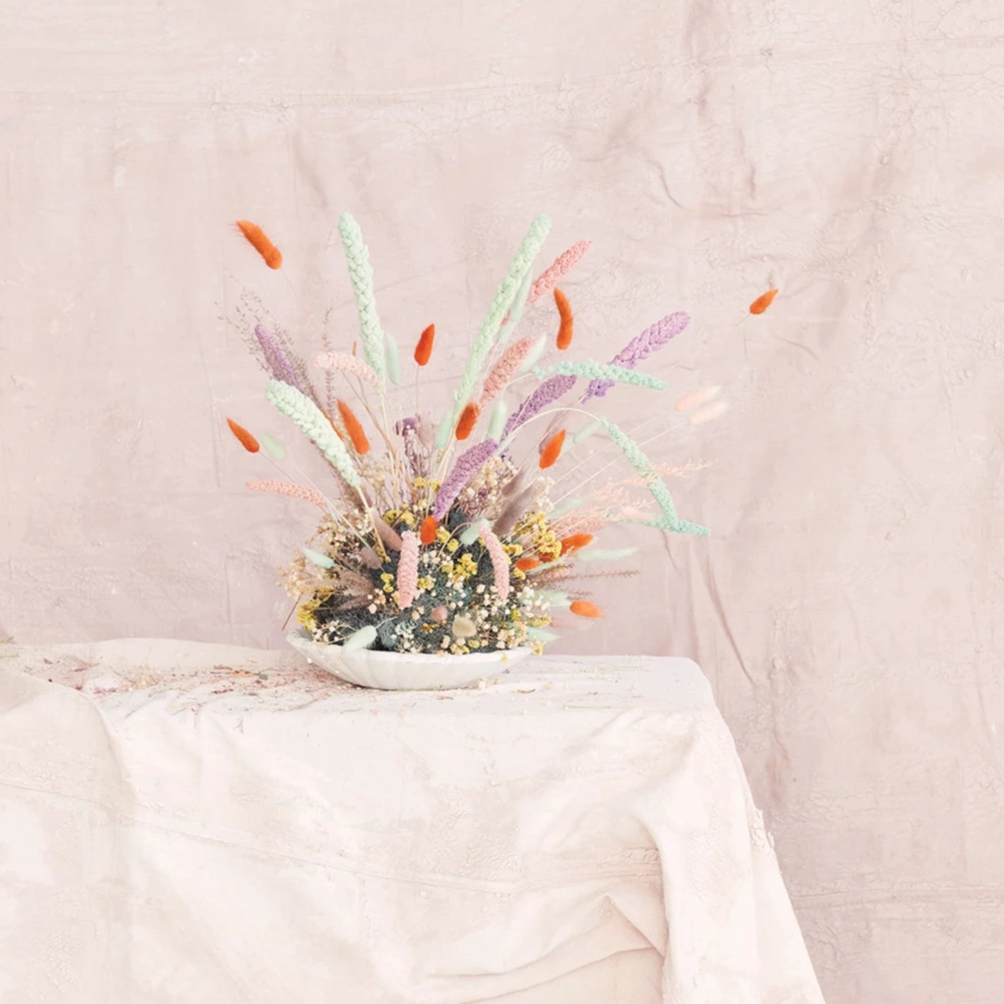 A bundle of dried bunny tail florals in a rich coral shade with long stems photographed with the other shades of bunny tail bunches that we sell on our website in shades of pink, natural and lavender.