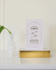 A cream box of 78 Tarot cards with an illustration of two hands and a star in between. All cards are beautifully illustrated with descriptions underneath and detailed with gold foiling.