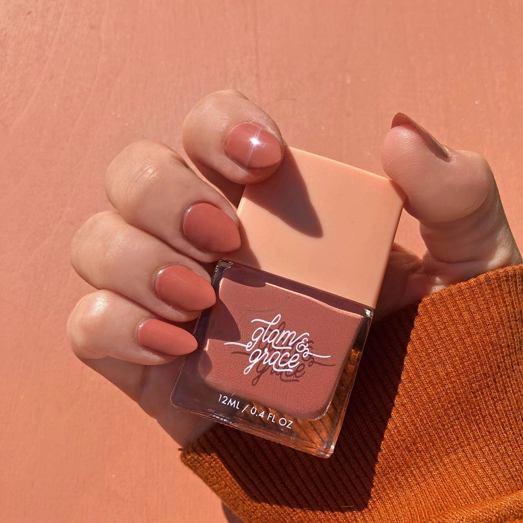 A rosie nail polish with a satin finish in a glass bottle with a peachy square lid.