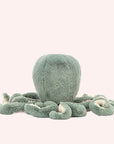 In front of a white background is a light blue stuffed octopus. The bottom of his tentacles is cream colored. 