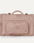 A nude colored pet carrier with an outside pocket for storing essentials and a zipper opening on both ends along with a handle on the top and two attachments for a shoulder strap option.