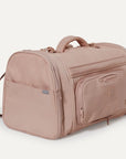A nude colored pet carrier with an outside pocket for storing essentials and a zipper opening on both ends along with a handle on the top and two attachments for a shoulder strap option. There is a mesh opening on the side of the carrier that can also be covered with a folded flap.