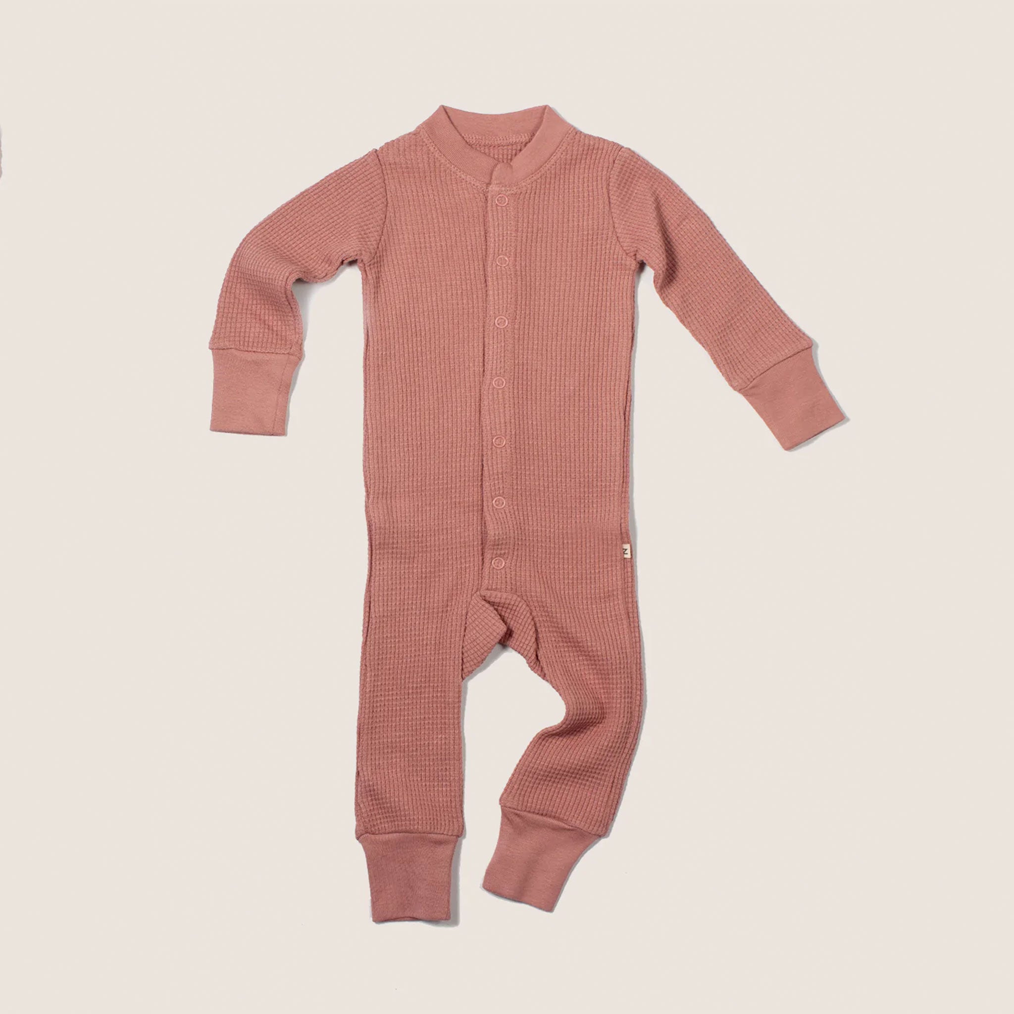 A dusty rose onesie pajamas set featuring a waffle knit material.