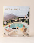 A book cover featuring a photo of 3 women around a pool outside of a midcentury home with a beautiful mountainous background. The title reads, " Slim Aarons Women".